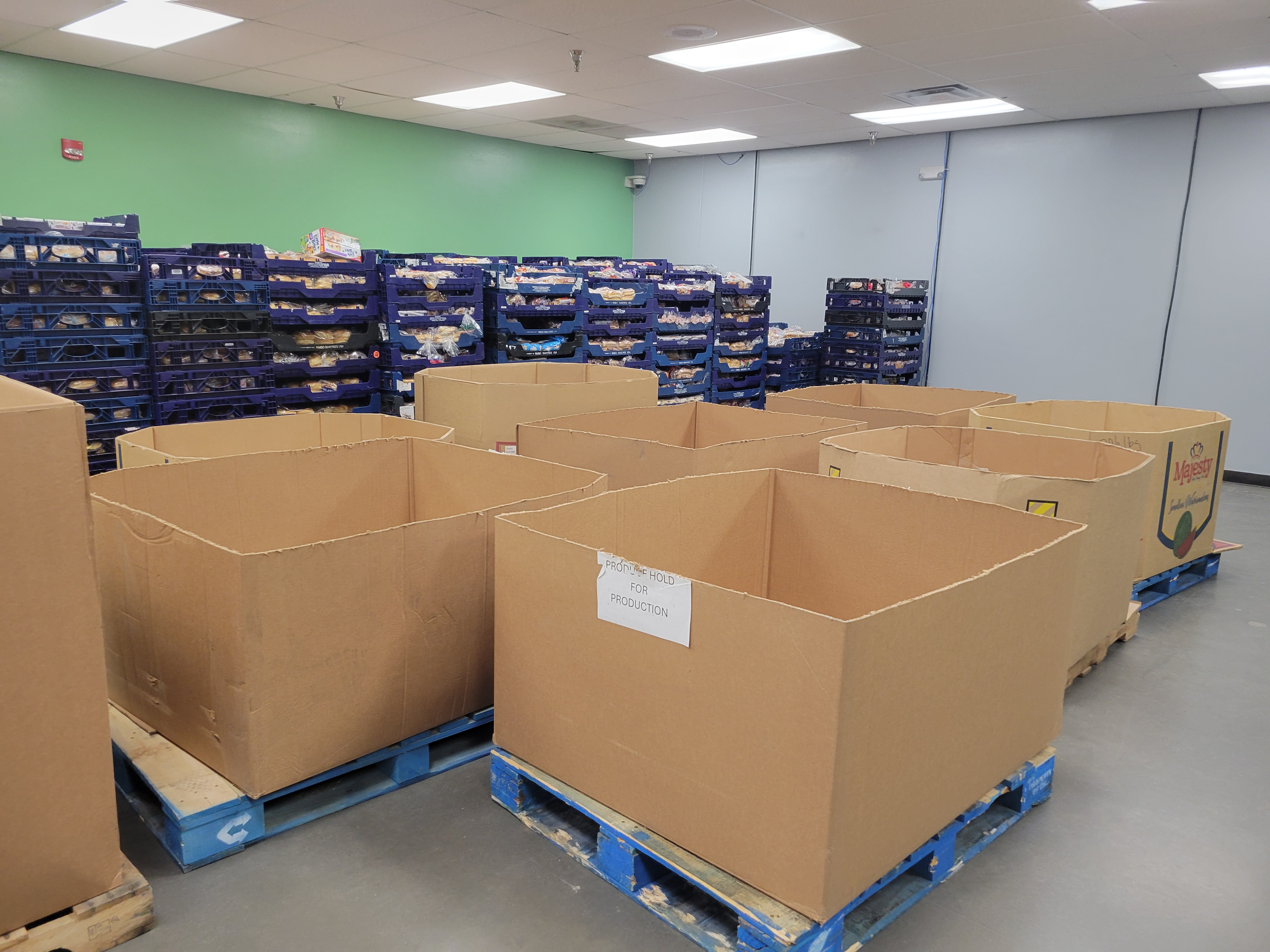 9 cardboard containers on pallets next to racks of bread.